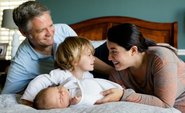 Mother and father with child smiling on a bed