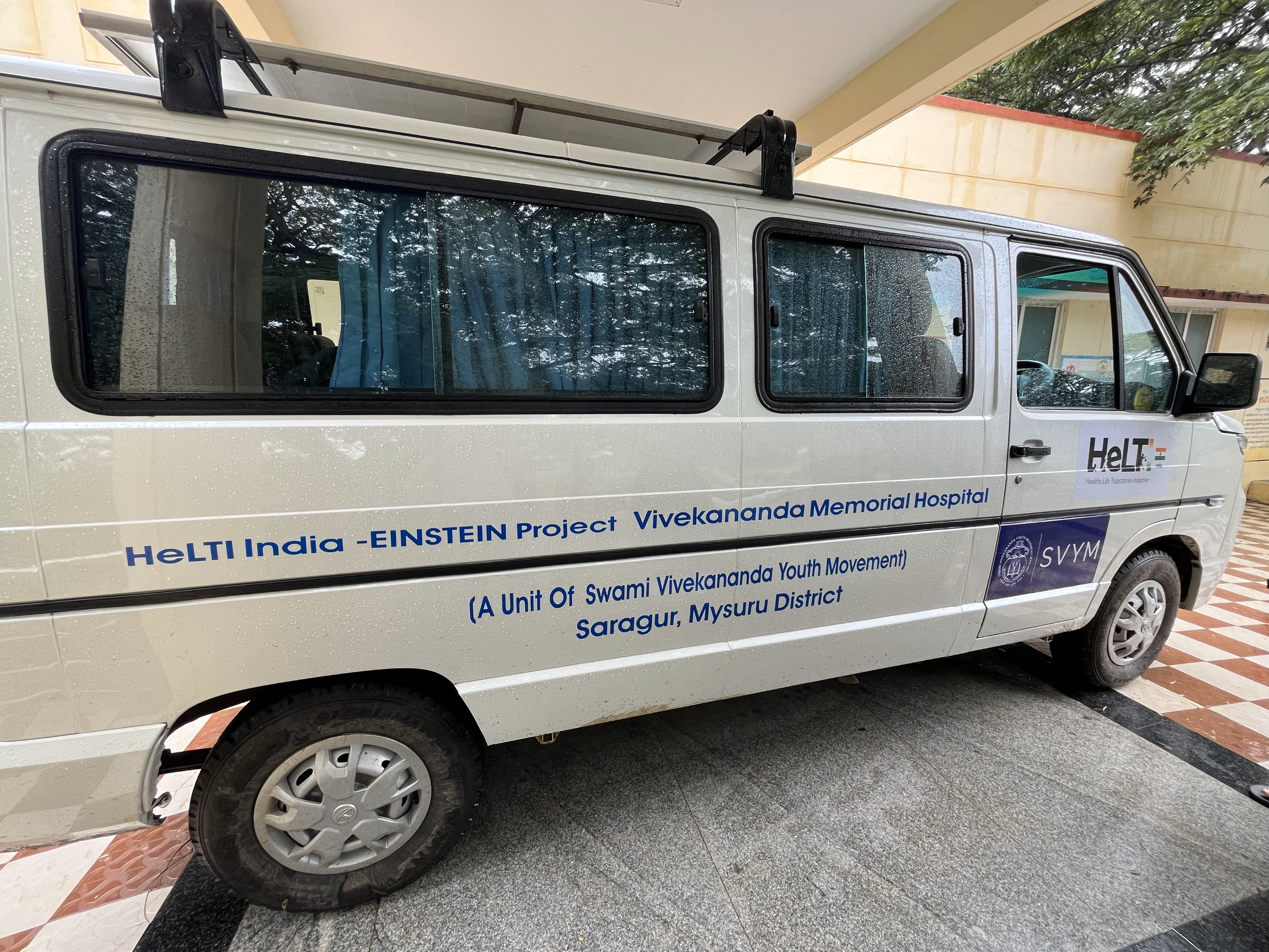 Left side view of white SVYM van with HeLTI India logo